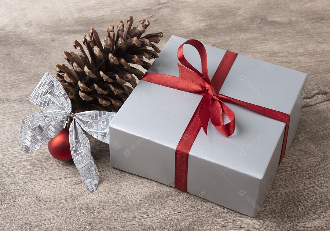 Caixa de presente, pinha, bola de natal e arco sobre a mesa de madeira.