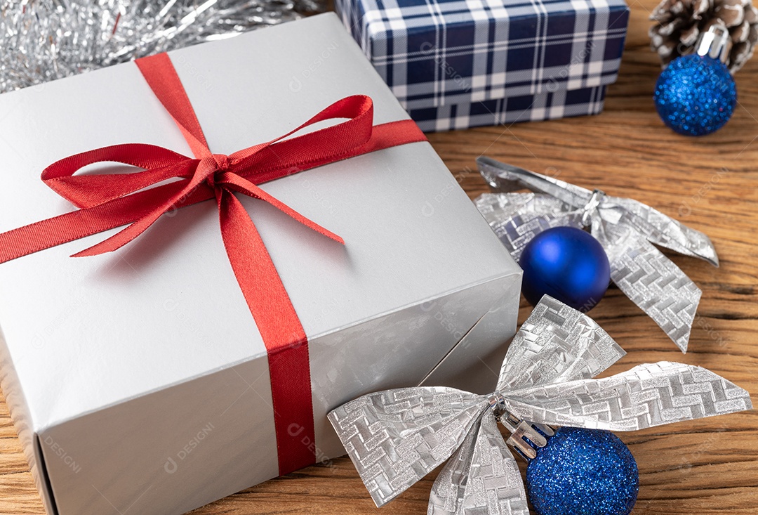 Caixa de presente, bolas de natal e arco sobre a mesa de madeira.