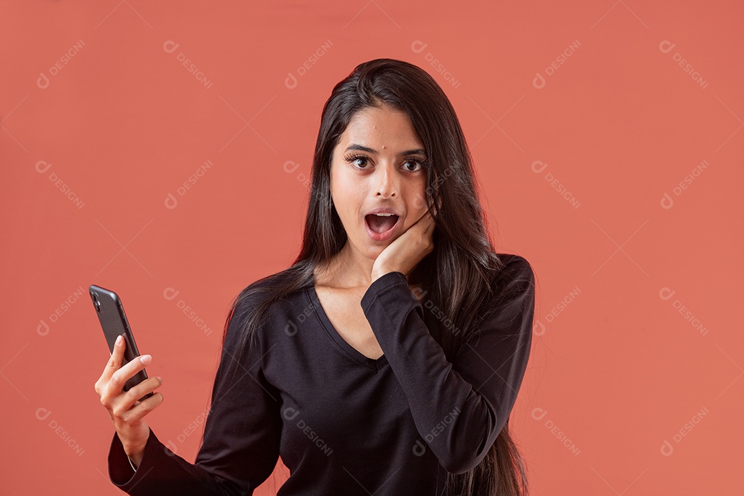 Linda mulher jovem segurando celular sobre fundo vermelho