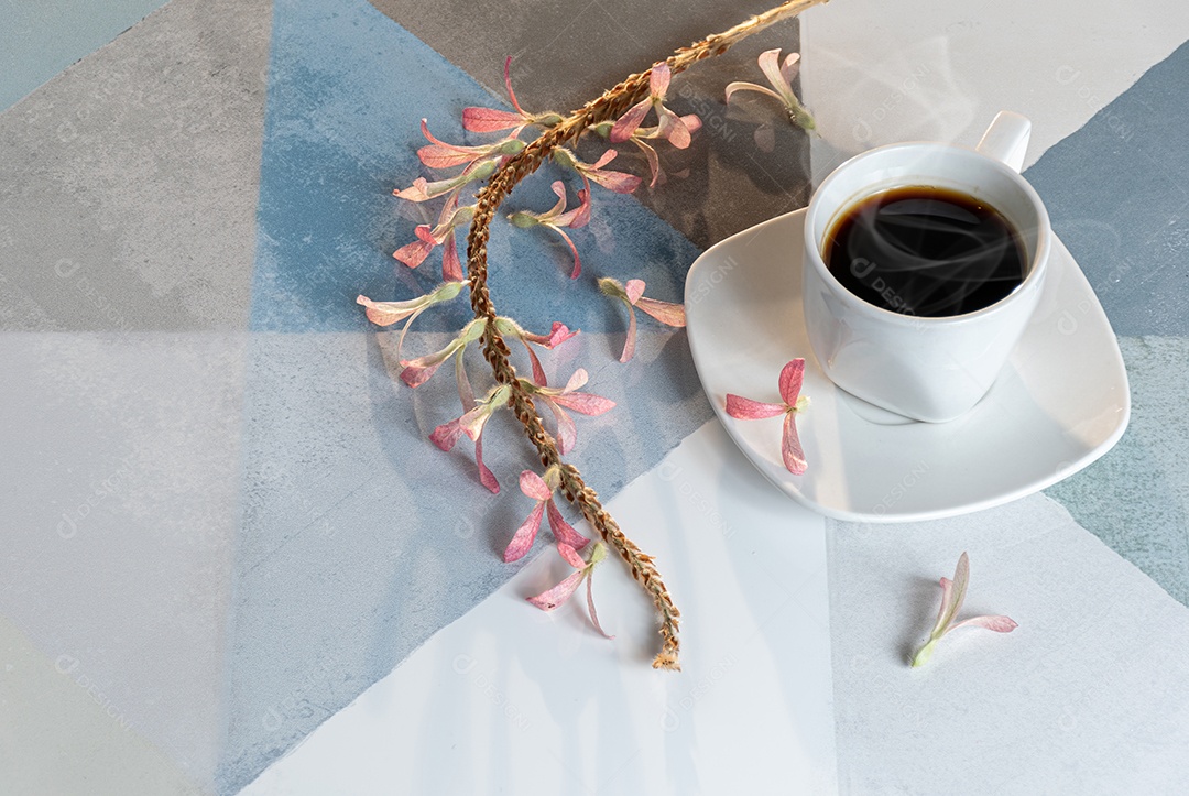 Xícara de café fumando em uma mesa quadriculada colorida ao lado de sementes