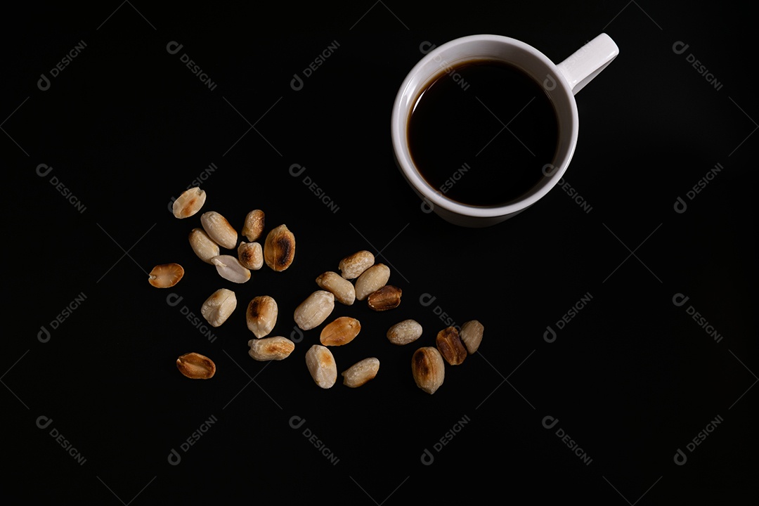 Café e amendoim torrado sem sal sobre fundo preto.