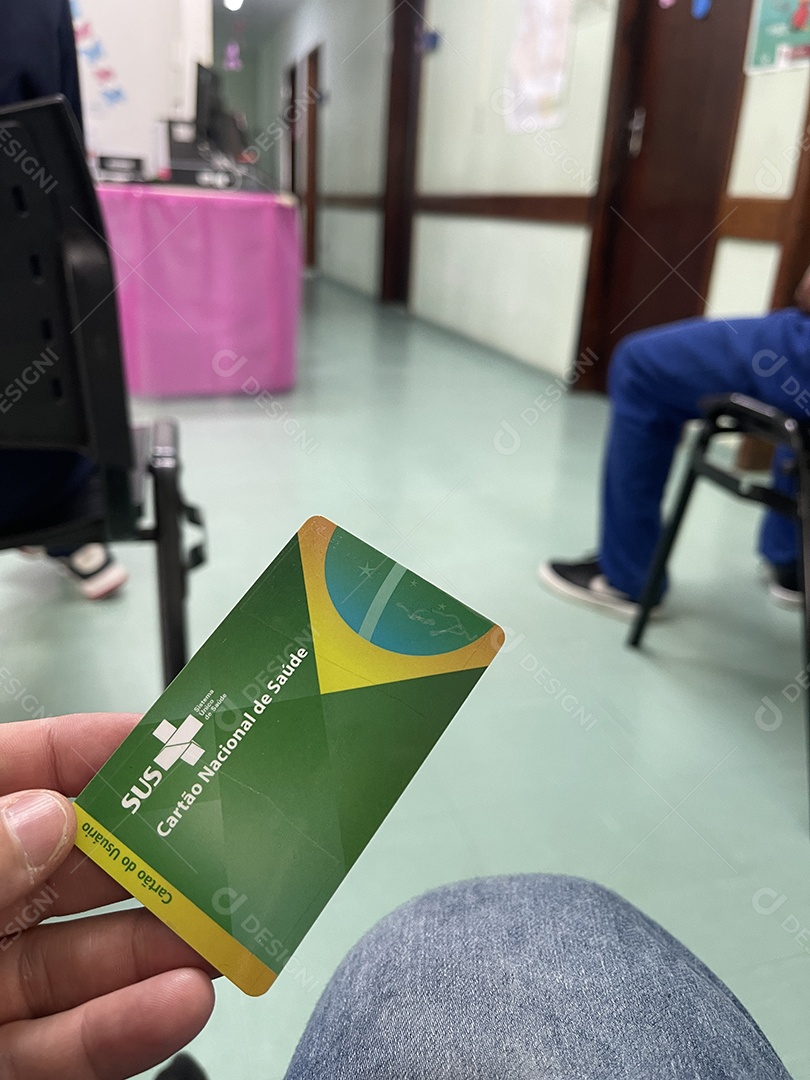 Homem na sala de espera do hospital com o Cartão Único de Saúde (SUS) do Brasil.
