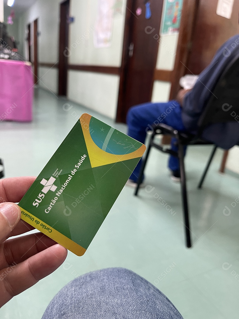 Homem na sala de espera do hospital com o Cartão Único de Saúde (SUS) do Brasil.