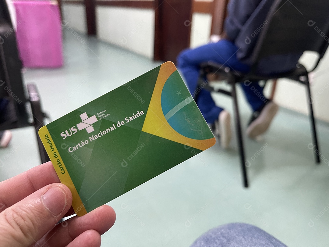 Homem na sala de espera do hospital com o Cartão Único de Saúde (SUS) do Brasil.