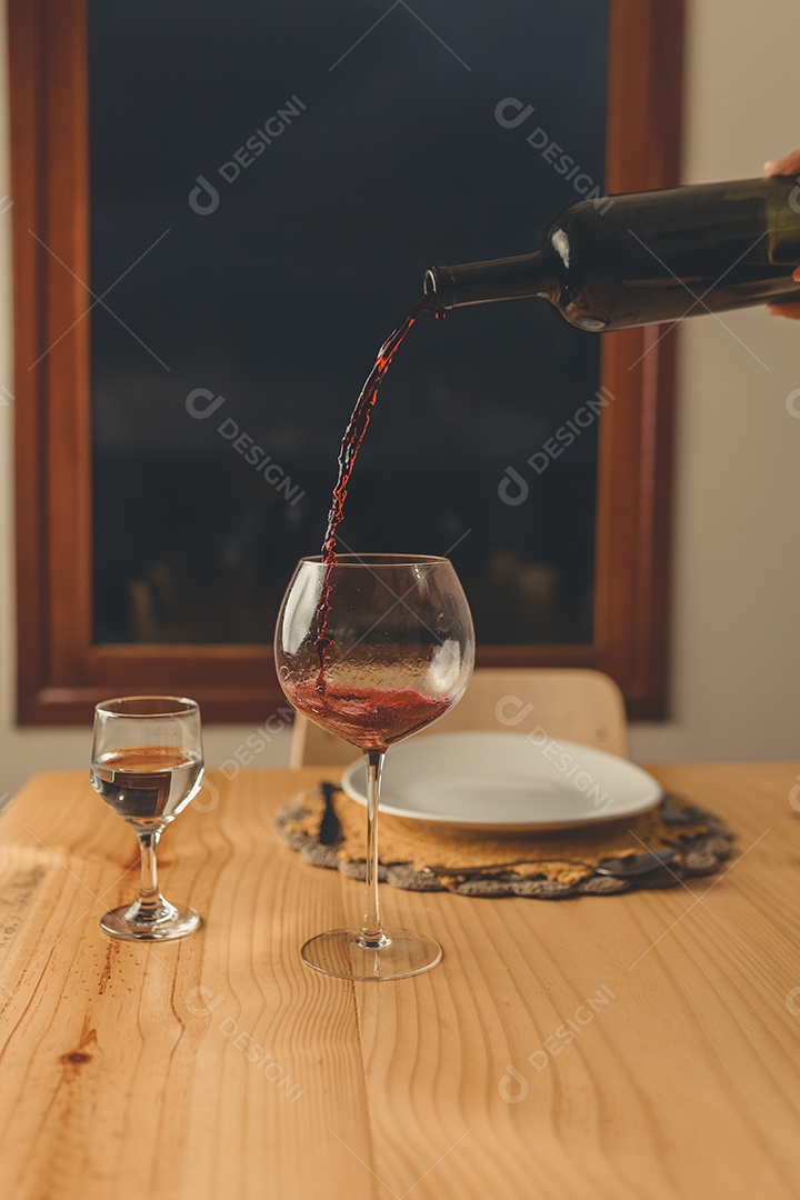 Mãos de pessoa colocando em taça sobre uma mesa de madeira