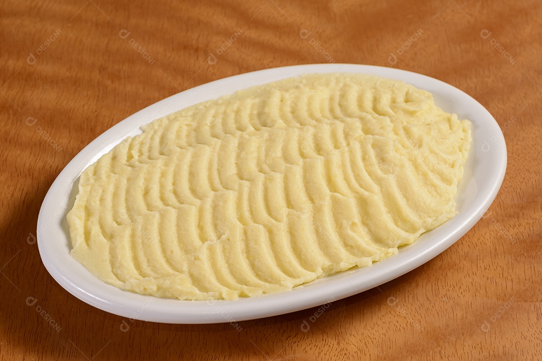 Purê de batata. Pequena porção em tigela branca sobre fundo de madeira.