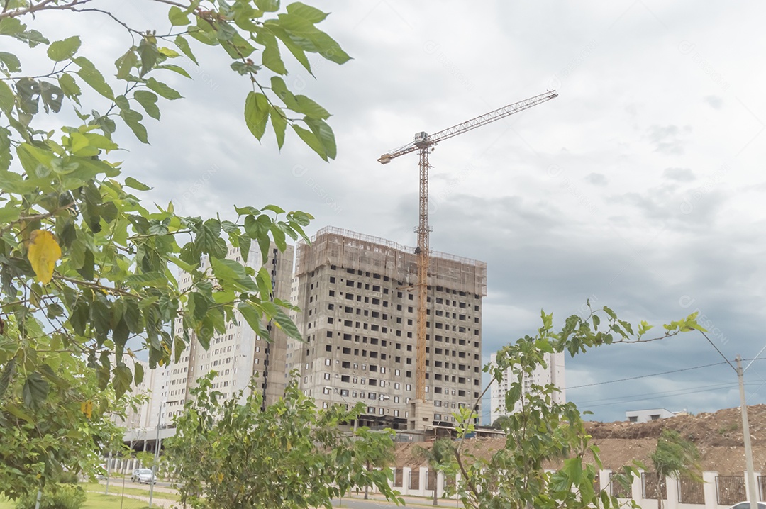 Edifício sendo construído com um guindaste de construção ao lado.