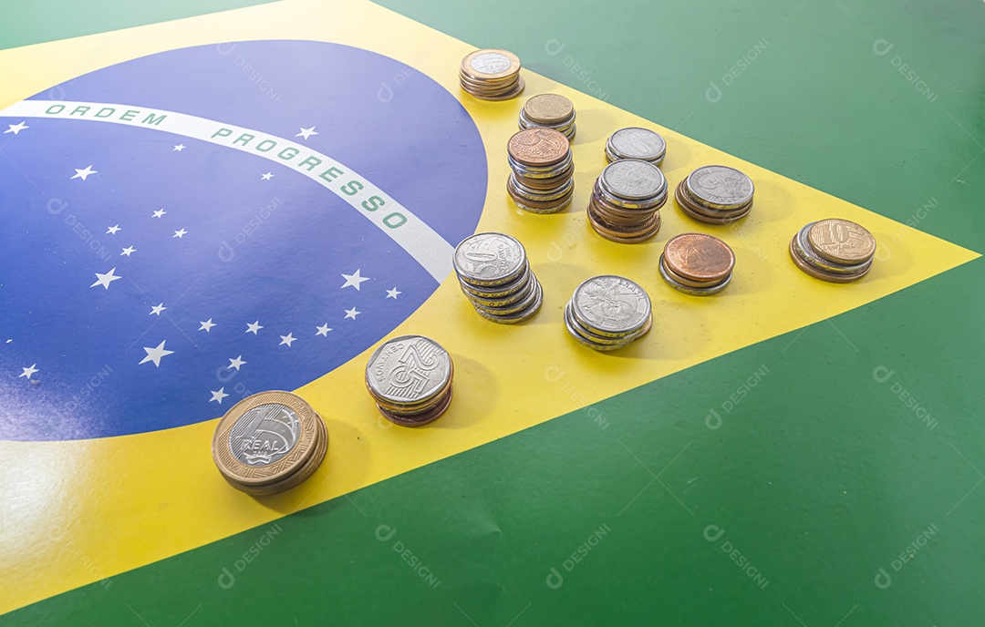 Ordem progresso bandeira brasileira com moedas reais brasileiras, conceito de decadência do dinheiro brasileiro.