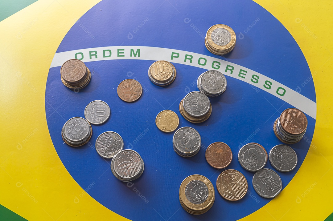 Ordem progresso bandeira brasileira com moedas reais brasileiras, conceito de decadência do dinheiro brasileiro.