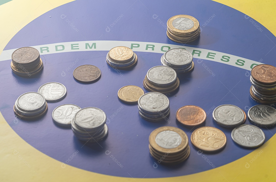 Ordem progresso bandeira brasileira com moedas reais brasileiras, conceito de decadência do dinheiro brasileiro.