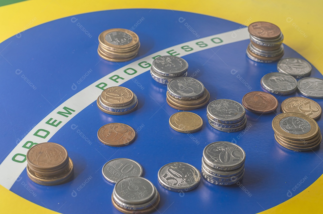 Ordem progresso bandeira brasileira com moedas reais brasileiras, conceito de decadência do dinheiro brasileiro.
