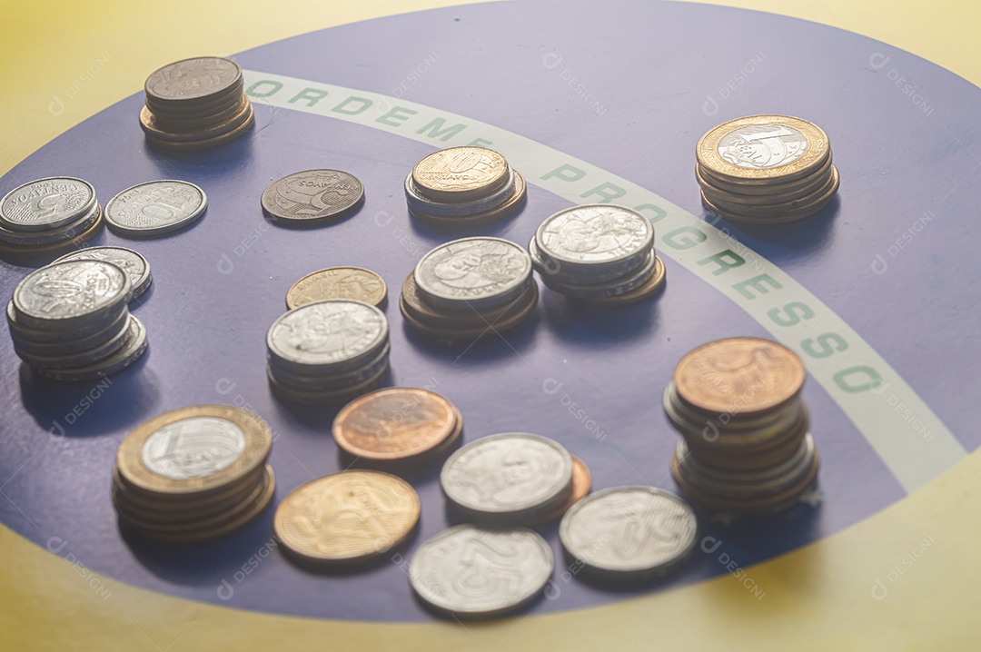 Ordem progresso bandeira brasileira com moedas reais brasileiras, conceito de decadência do dinheiro brasileiro.
