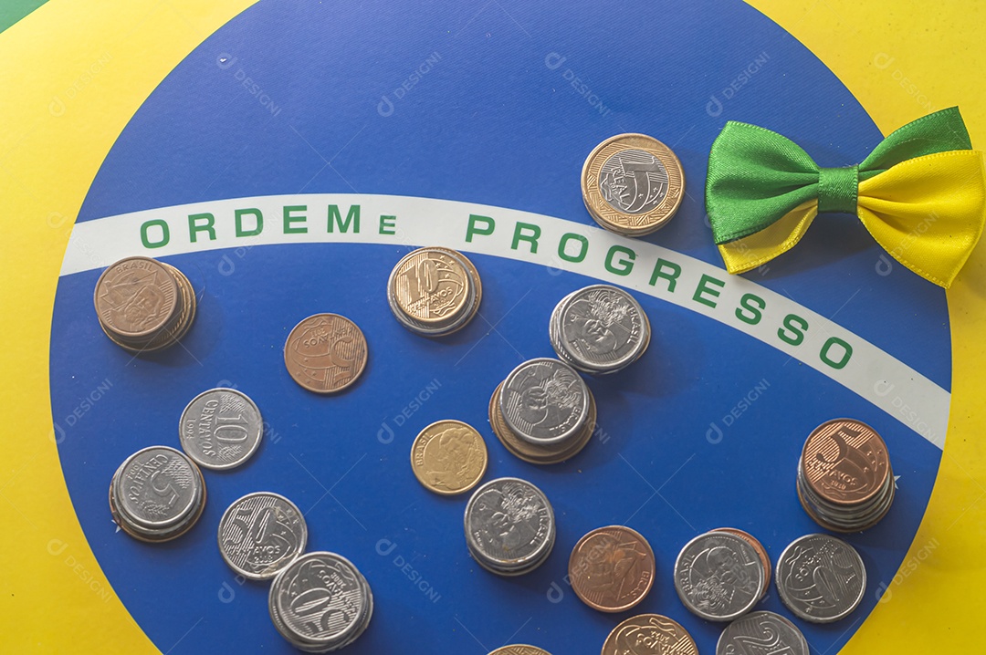 Ordem progresso bandeira brasileira com moedas reais brasileiras, conceito de decadência do dinheiro brasileiro.