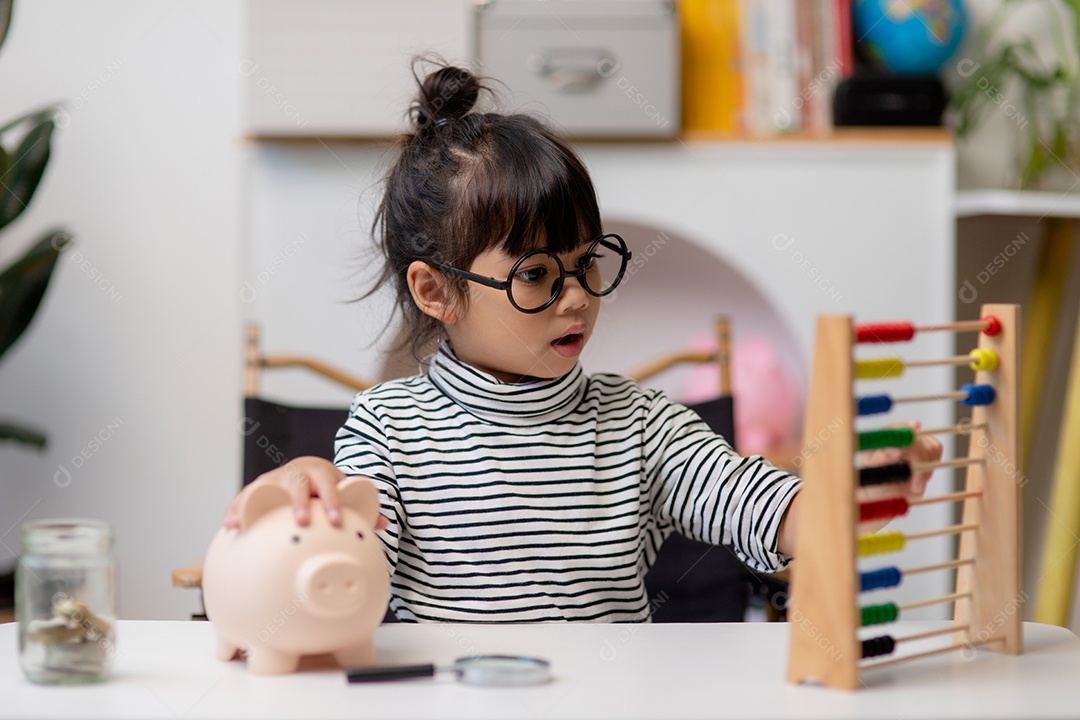 Menina asiática economizando dinheiro em um cofrinho, aprendendo