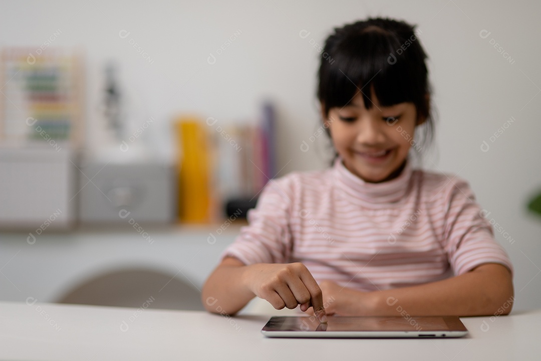 Menina bonita asiática tocando a tela do tablet digital em cima da mesa