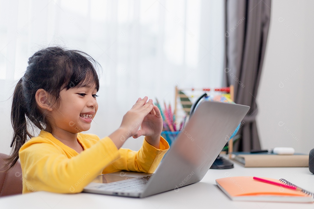 Primeiro dia na escola. Menina asiática que usa um laptop