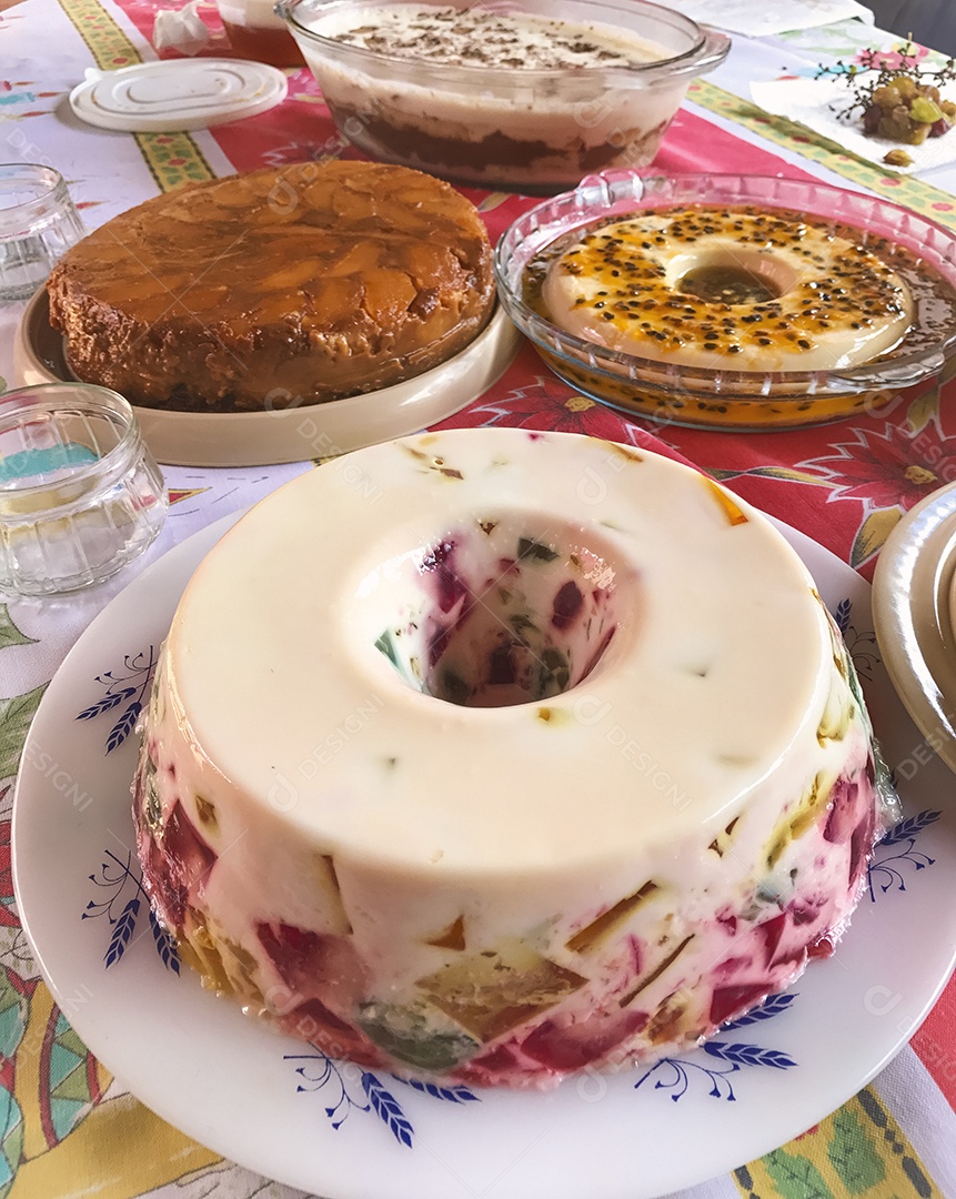 Gelatina colorida, mousse de maracujá, creme de coco e torta de maçã. Mesa de famosos doces brasileiros.