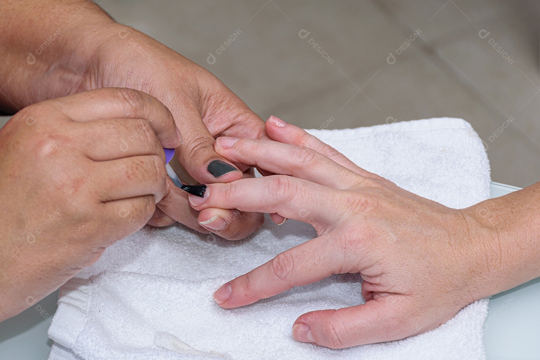 Manicure com palito de madeira com algodão para limpar a cutícula da cliente.