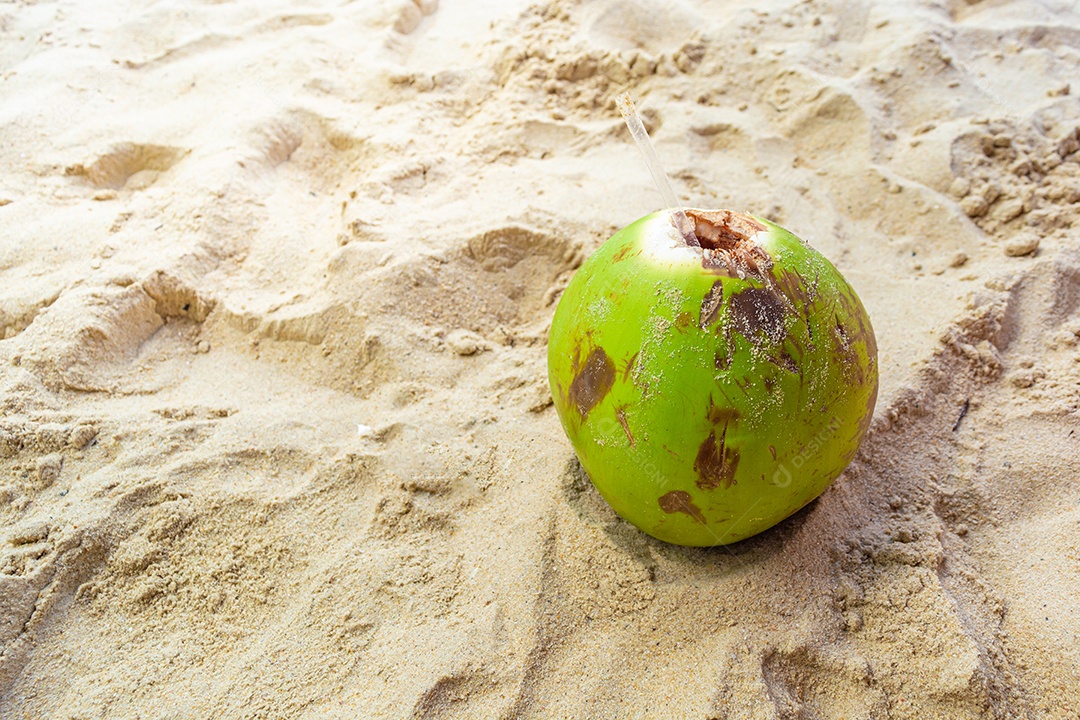Coco verde com água e palha em uma praia brasileira, símbolo