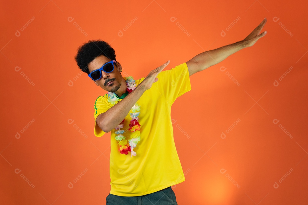 Brazilian soccer fan celebrating isolated on orange background. Excited football fan cheering.