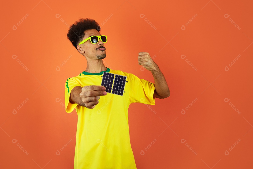 Jogador de futebol - homem negro comemorando segurando painel solar fotovoltaico isolado em laranja