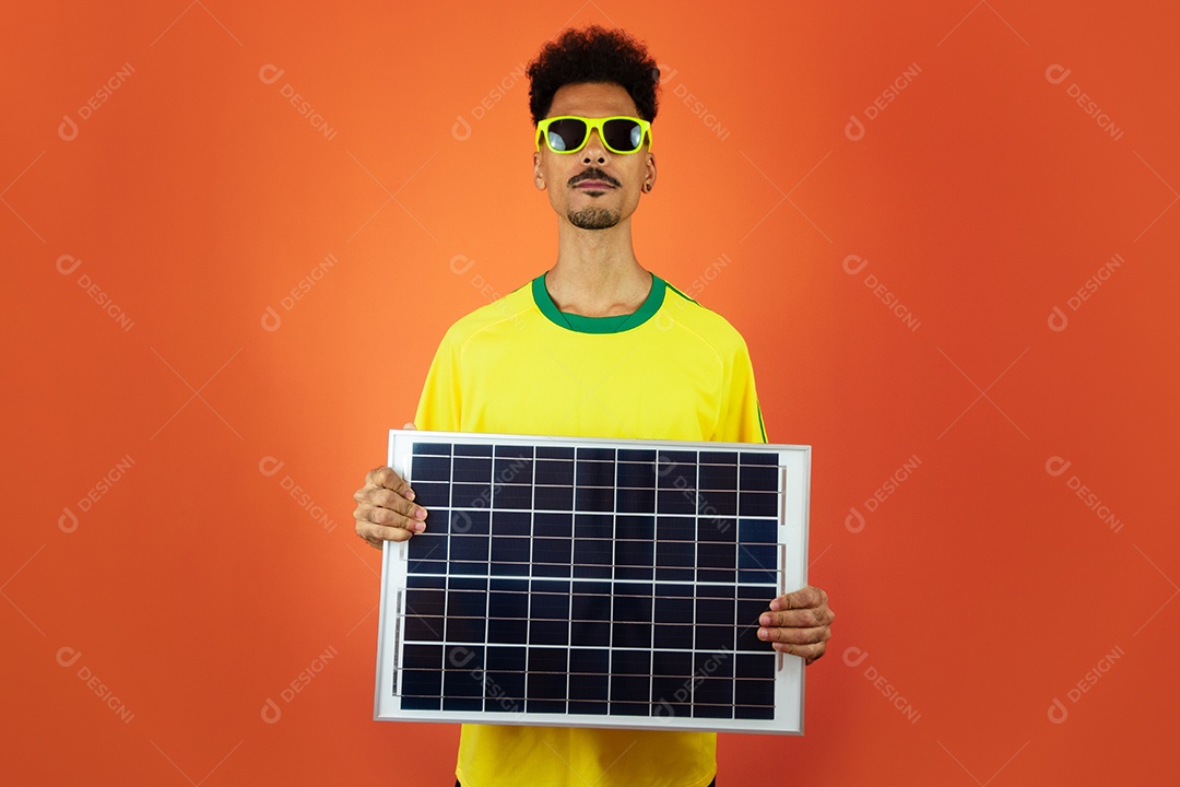 Jogador de futebol - homem negro comemorando segurando painel solar fotovoltaico isolado em laranja