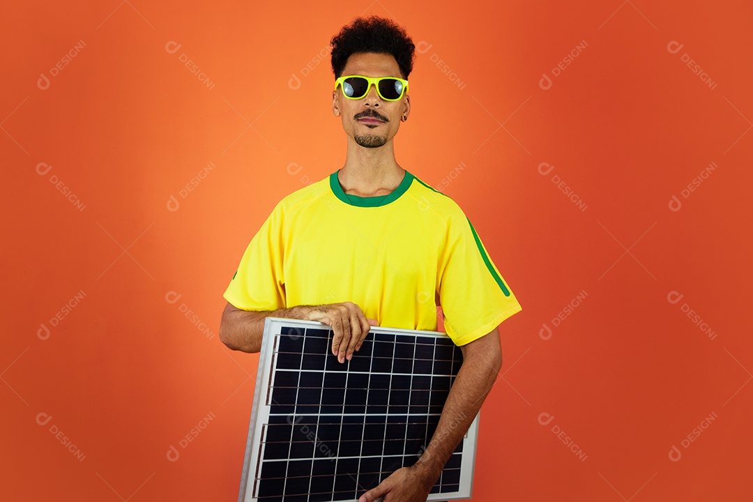 Jogador de futebol - homem negro comemorando segurando painel solar fotovoltaico isolado em laranja