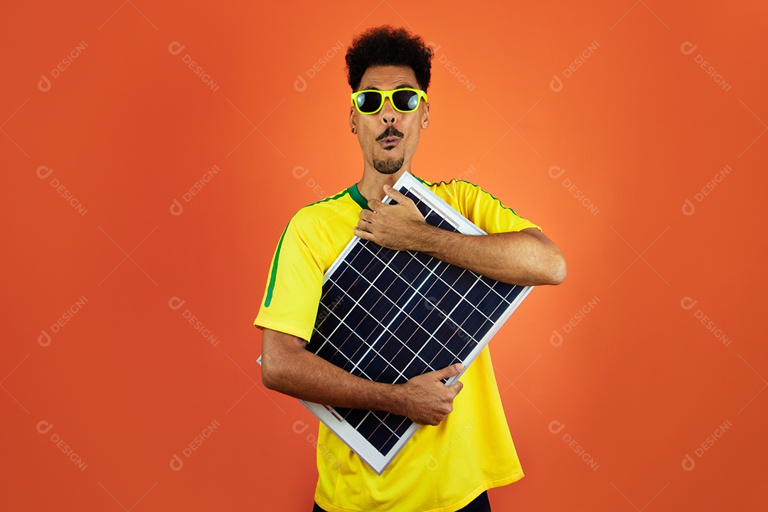 Football player - black man celebrating holding photovoltaic solar panel isolated on orange