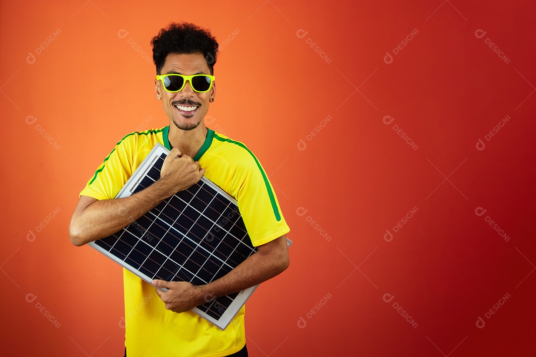 Jogador de futebol - homem negro comemorando segurando painel solar fotovoltaico isolado em laranja