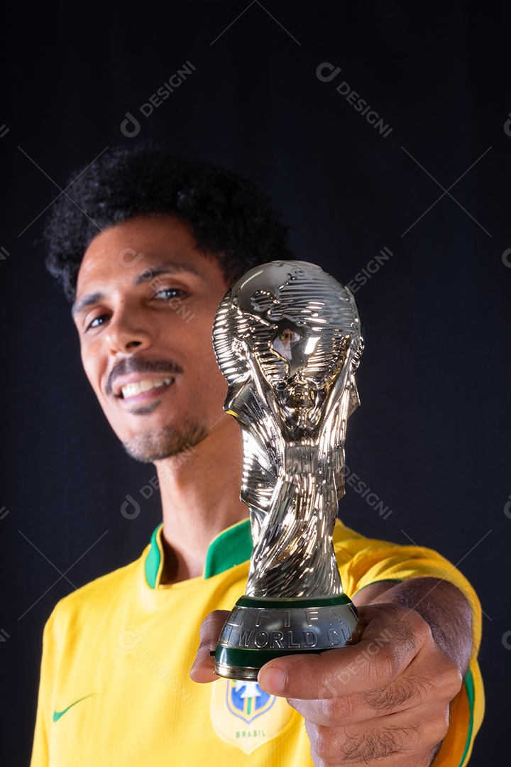 Jogador negro de futebol brasileiro segurando o troféu vencedor
