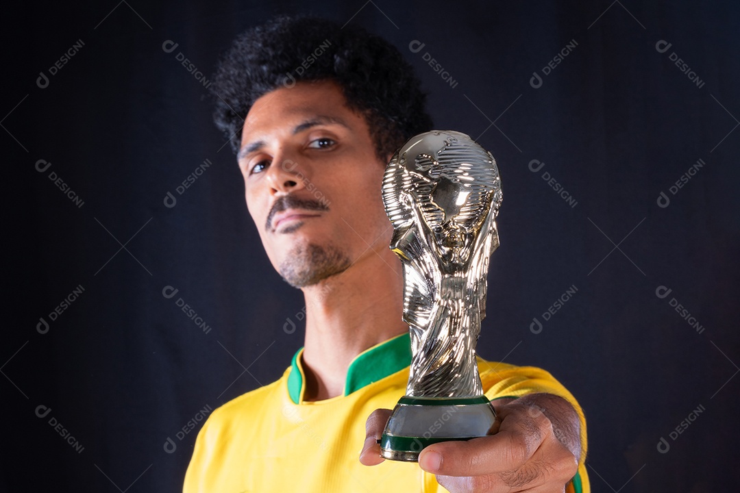 Jogador negro de futebol brasileiro segurando o troféu