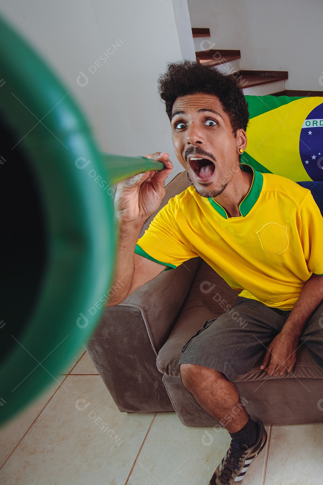 Homem negro com camisa amarela na sala assistindo TV