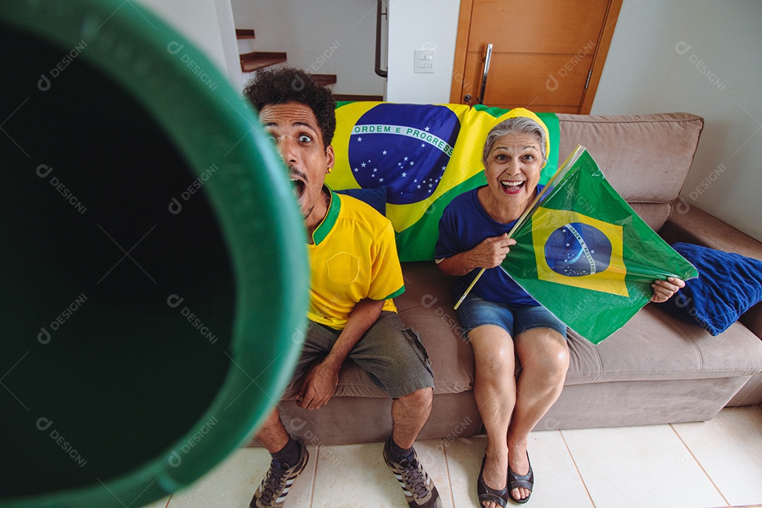 Homem negro com camisa amarela na sala assistindo TV