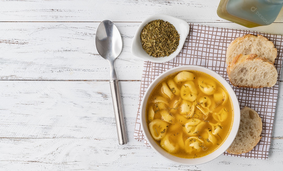 Sopa de brodo de cappelletti ou tortellini em uma tigela com fatias de pão