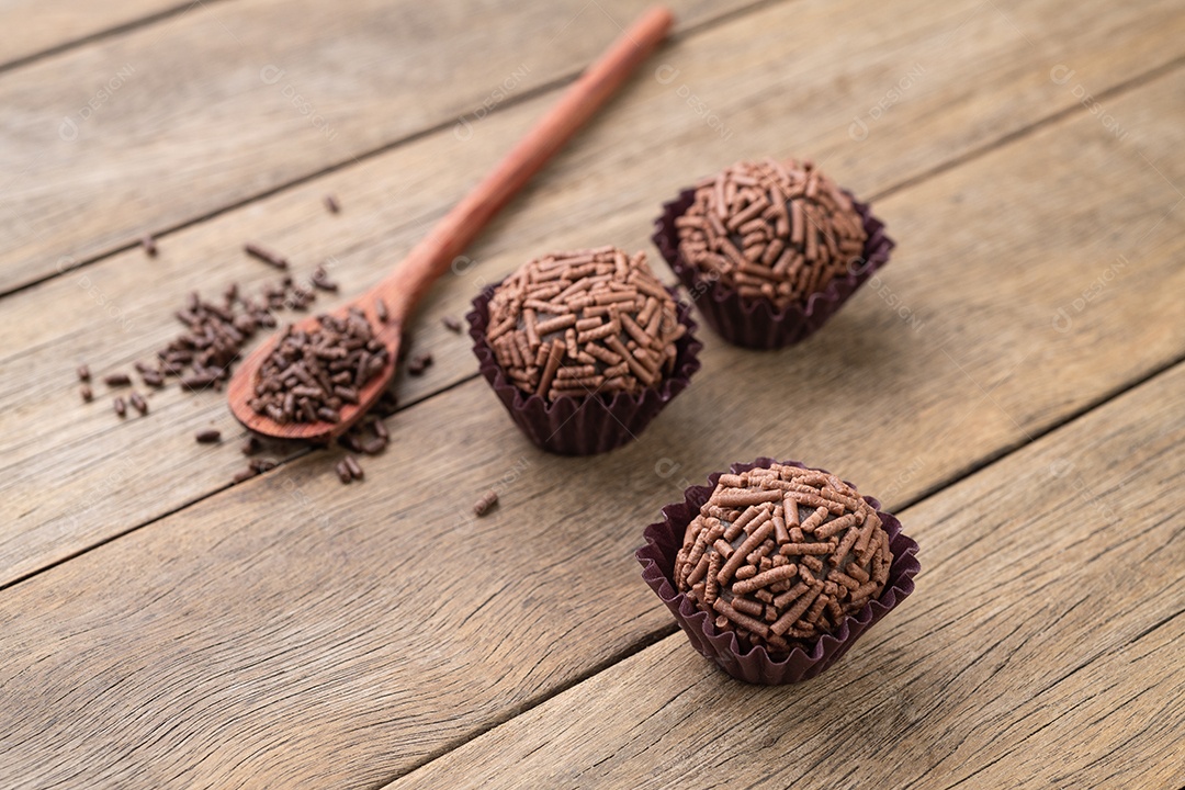 Típicos brigadeiros de chocolate brasileiros sobre mesa de madeira.