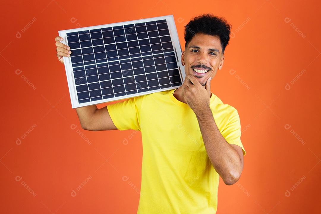 Homem negro bonito segurando um cofrinho e painel solar isolado em laranja.