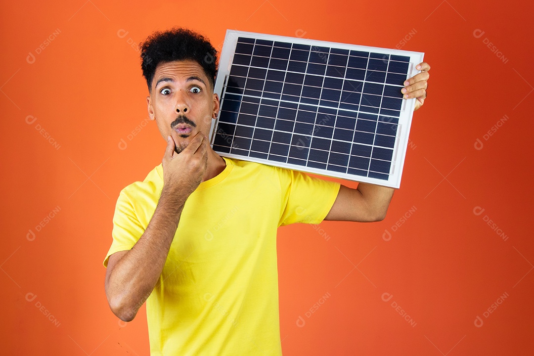 Homem negro bonito segurando um cofrinho e painel solar isolado em laranja.