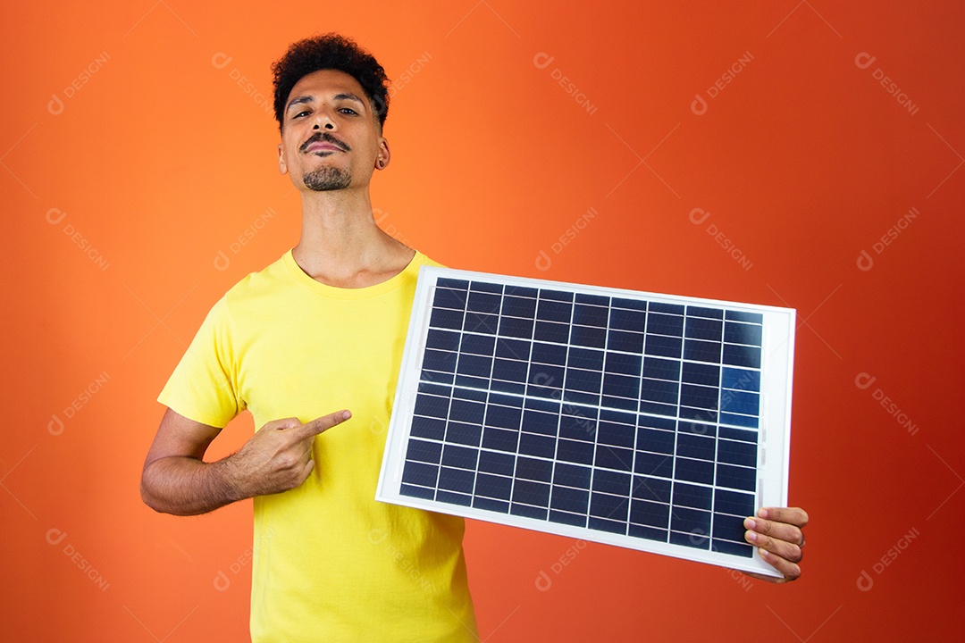 Homem negro bonito segurando um cofrinho e painel solar isolado em laranja.