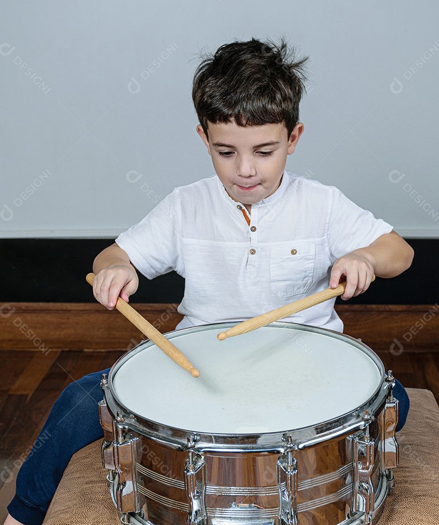 Criança de 7 anos olhando para a câmera e tocando bateria.