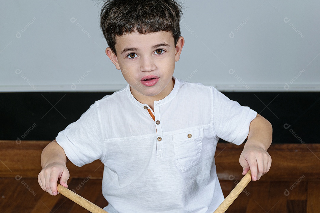 Criança de 7 anos olhando para a câmera e tocando bateria.