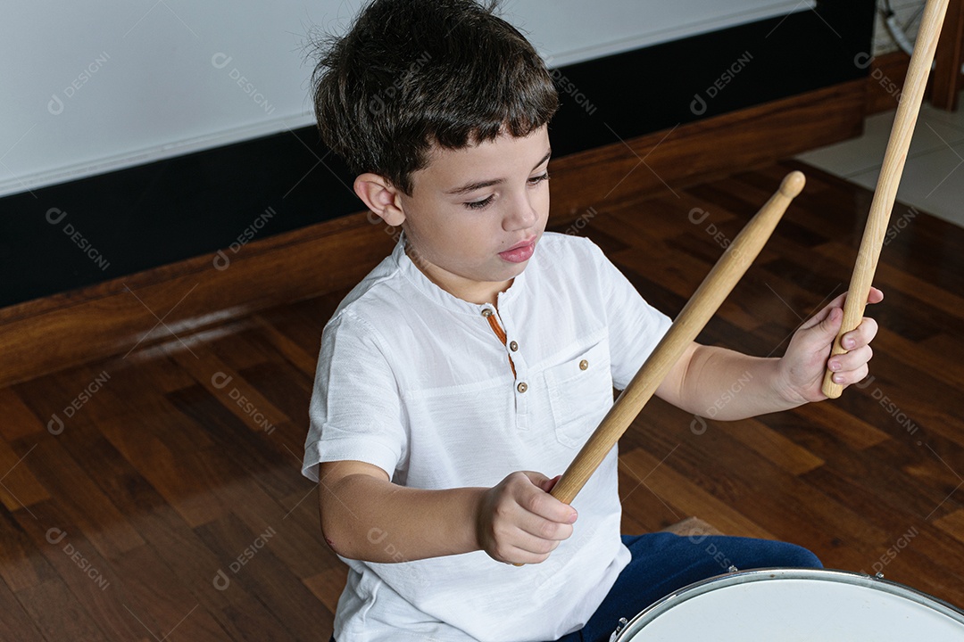 Criança de 7 anos olhando para a câmera e tocando bateria.