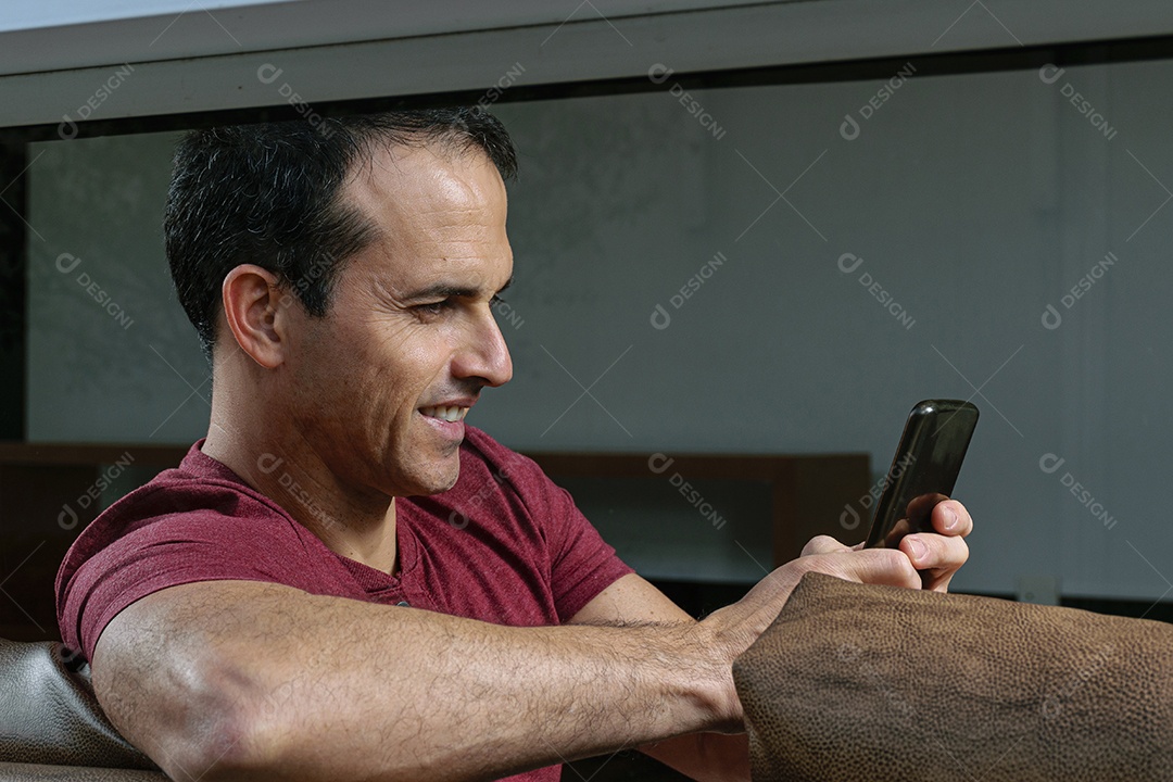 Homem jovem sentado sobre sofá sobre conforto de sua casa