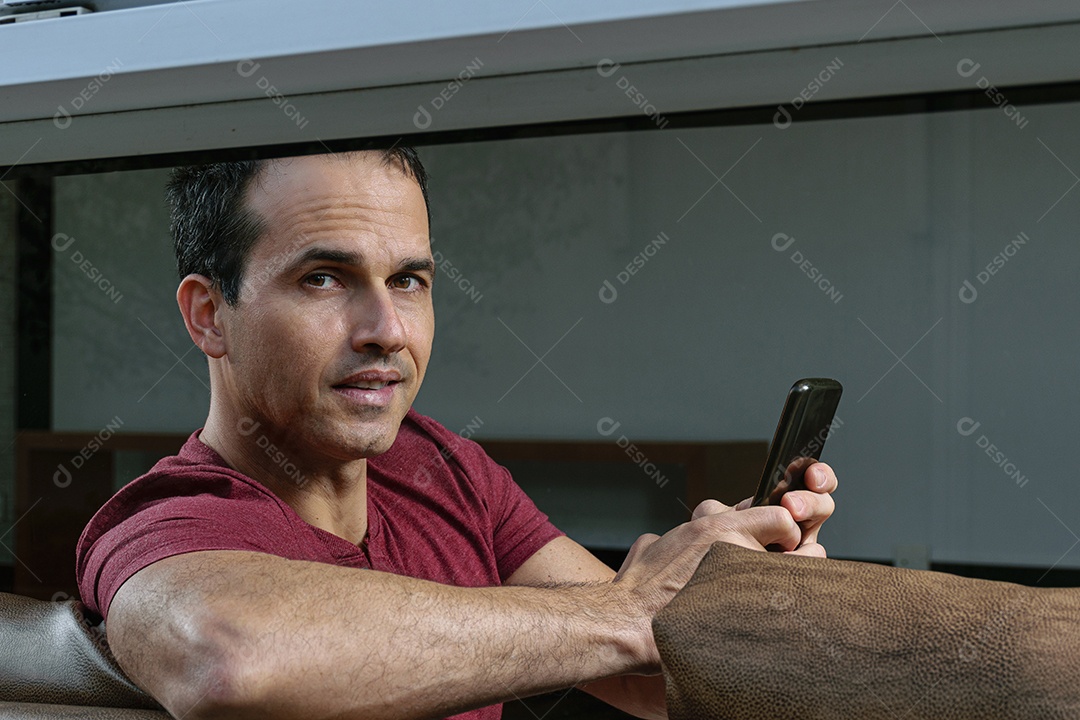 Homem jovem sentado sobre sofá sobre conforto de sua casa