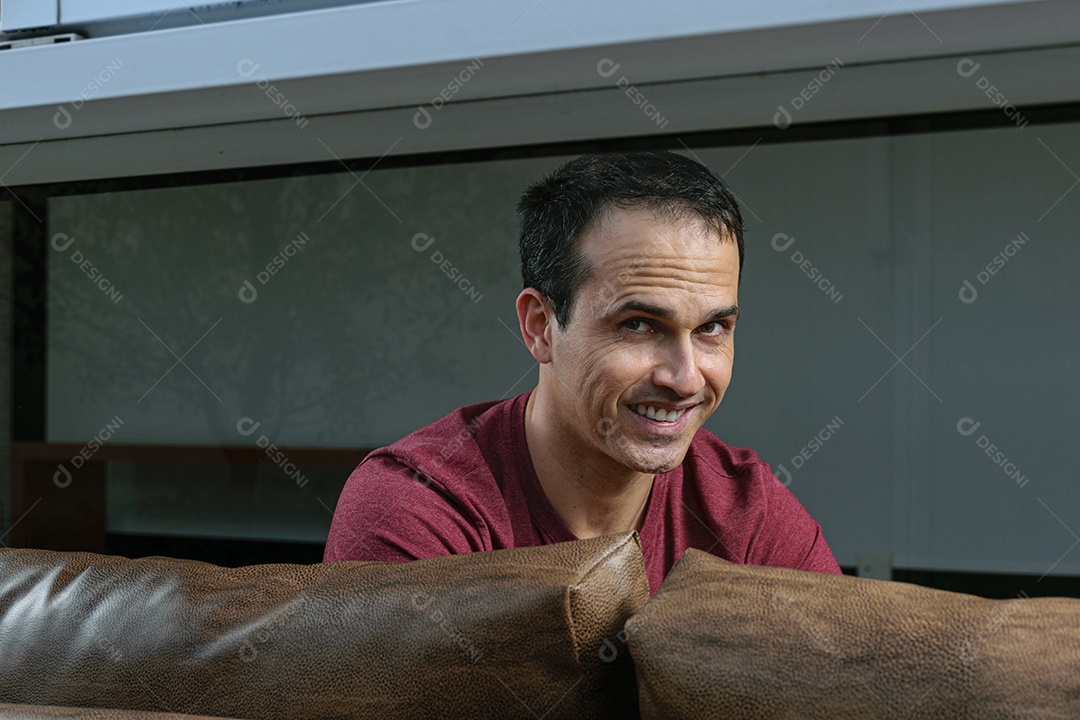 Homem jovem sentado sobre sofá sobre conforto de sua casa