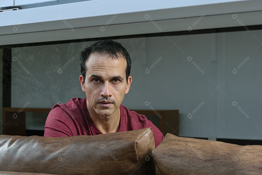 Homem jovem sentado sobre sofá sobre conforto de sua casa