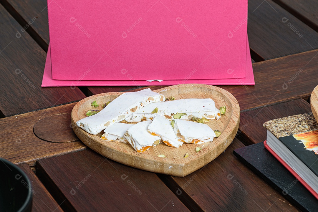 Caneca amarela com um caderno ao fundo, com dois brigadeiros desfocados
