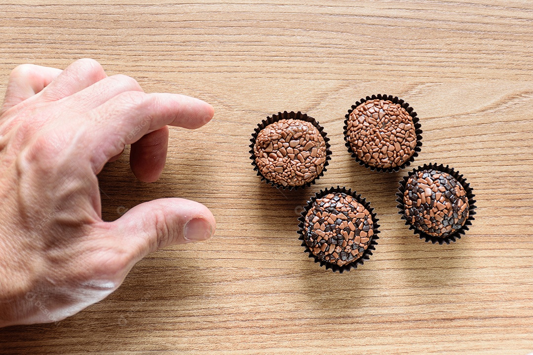 Quatro brigadeiros sobre uma mesa de madeira.