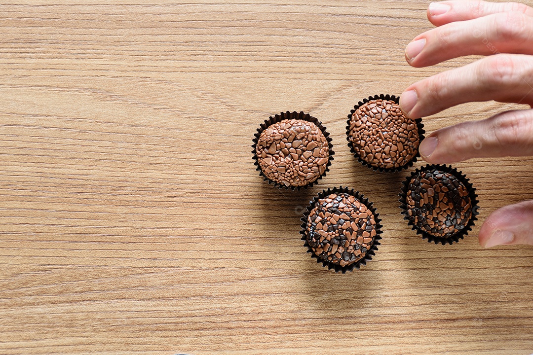 Quatro brigadeiros sobre uma mesa de madeira.