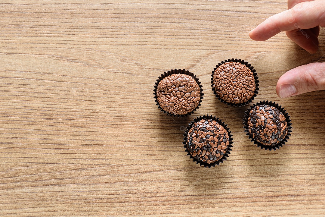 Quatro brigadeiros sobre uma mesa de madeira.