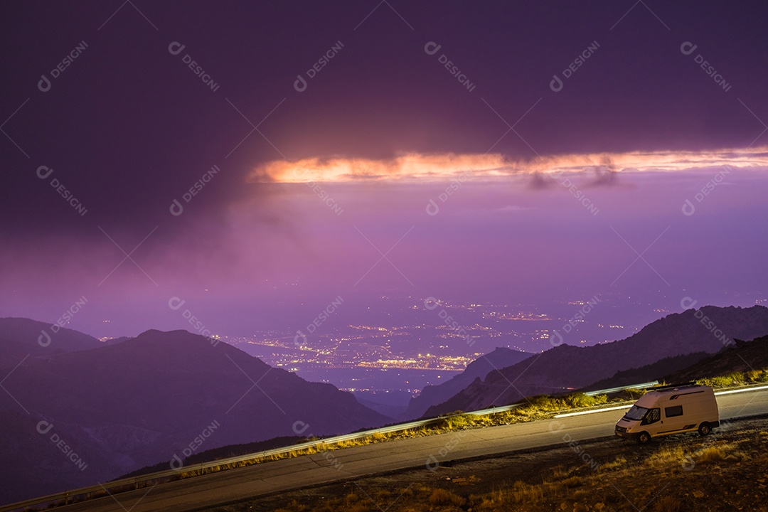Vista da Serra Nevada com pequena estrada e cidade de Granada ao pôr do sol.